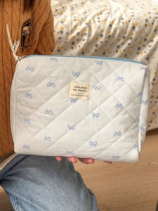 Detail of quilted cotton makeup bag with blue bow prints and ribbon zipper puller