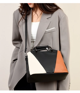 Close-up of tricolor pebble leather tote bag worn by a model in a gray suit