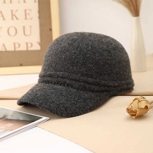Deep grey knitted wool blend baseball cap for winter shown in a cozy home setting