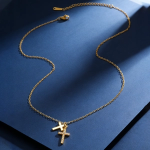 Detail of gold-plated stainless steel cross necklace with shimmering cubic zirconia inlay