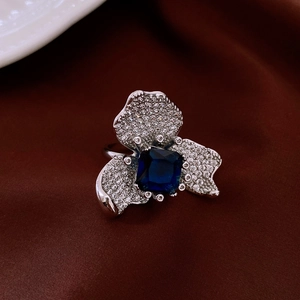 Détail macro d'une bague fleur vintage avec gemme bleu foncé et zircons blancs étincelants