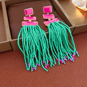 Detail of pink geometric top with turquoise beaded tassels on brown leather display