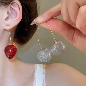 Détail de boucles d'oreilles cerises avec résine pailletée et crochets métalliques