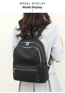 Detalle de mochila de nailon acolchado negro con cremalleras plateadas en modelo