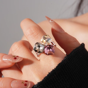 Detailed view of large square-cut pink, grey, and champagne crystals on a silver ring
