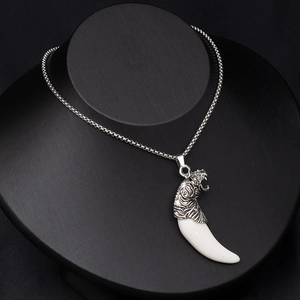 Detailed close-up of a vintage tiger head and white wolf tooth pendant on a bead chain