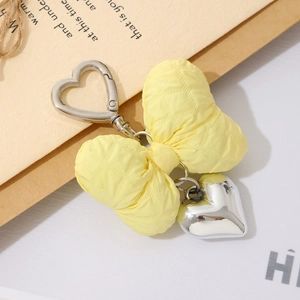 Chic yellow macaron cotton-filled bow keychain with silver heart pendant and metal clasp