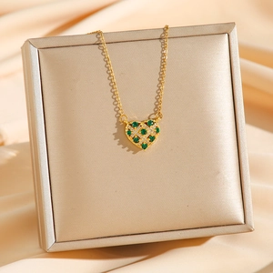 Collier cœur doré élégant avec zircon vert incrusté sur un support champagne