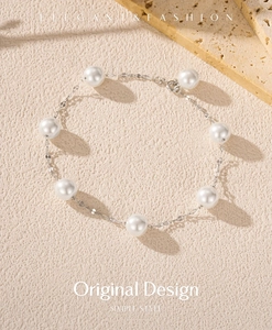 Macro view of S925 silver pearl bracelet with eight round pearls on a textured surface