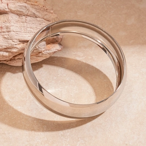 Detail showing the polished silver wide band cuff bracelet on textured marble stone surface