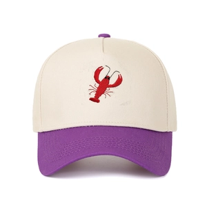 Detail of red lobster embroidery on a beige and purple contrast cotton baseball cap