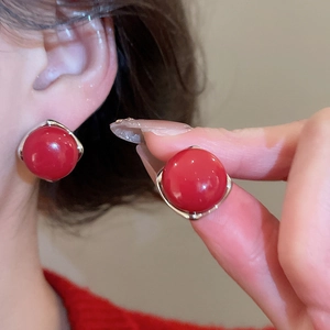 Detailed view of red round bead earrings with silver bezel setting worn on ear