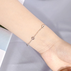Macro detail of minimalist silver chain bracelet with gear pendants on wrist
