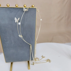 Detailed view of a golden butterfly headband with elegant pearls and long hanging tassels