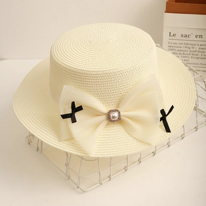 Detail showing the cream boater hat weave with a large chiffon bow and pearl decoration