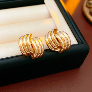 Detailed close-up of gold interlaced hoop earrings on white jewelry box padding