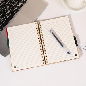 Retro kraftpapier A5 spiraalnotitieboek met indextabbladen en pen op bureaugeplaatst