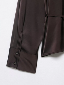 Detail shot of a dark brown satin shirt sleeve showing the cuff and two dark buttons