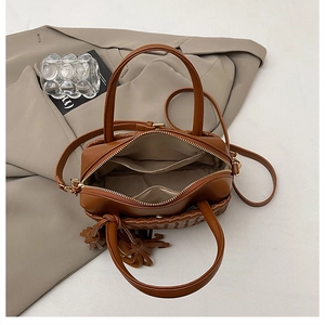 Top view of woven leather handbag featuring multiple interior pockets on beige fabric