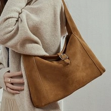 Close-up of caramel brown woven leather tote with central metal buckle and matte texture