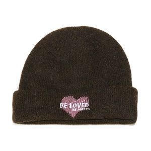 Detalle del bordado de corazón rosa con texto BE LOVED en un gorro de punto marrón