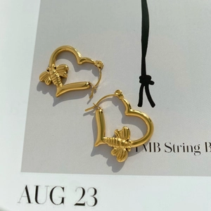 Minimalist gold heart earrings with bee embossed design on a stylish paper background