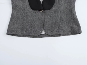 Close-up of gray herringbone fabric blazer with black lapel and single button detail
