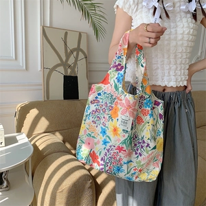Dettaglio della borsa shopper floreale con etichetta logo e trama in tela resistente