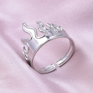 Detail of adjustable silver flame ring displayed on a smooth pink satin fabric background