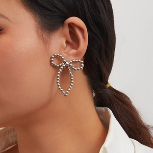 Detail of silver beaded bow earring with long tassel pendant on model side profile
