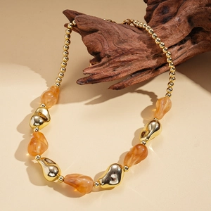 Detail of acrylic amber beads and gold metallic irregular spheres on a designer necklace