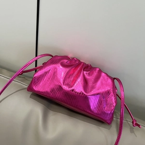 Metallic rose red dumpling bag with ruched texture on a beige sofa, stylish crossbody bag