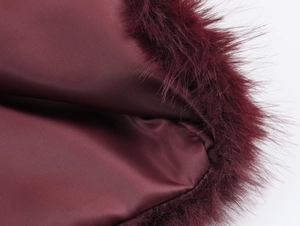 Detail of burgundy satin dress showing faux fur trim and fine stitching craftsmanship
