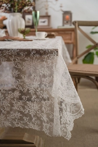 Close-up of white lace tablecloth with delicate floral embroidery and scalloped edges