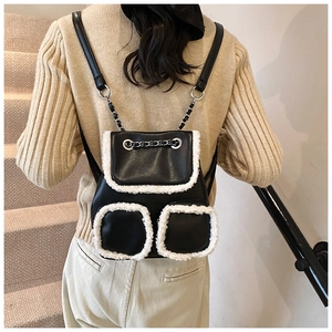 Detail of mini backpack featuring black leather with white faux fur trim and chain straps