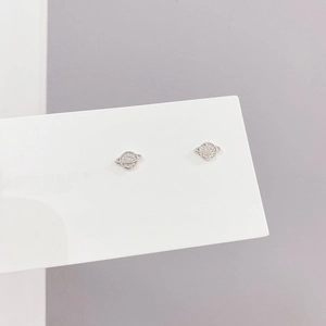 Detalle de pendientes de planeta plateados con circonitas incrustadas en tarjeta blanca