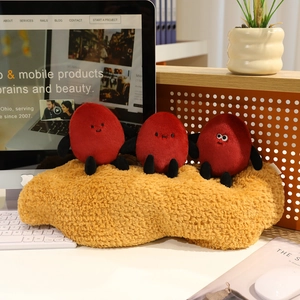 Close-up of three cute red bean plush dolls with funny faces on a yellow fuzzy cushion