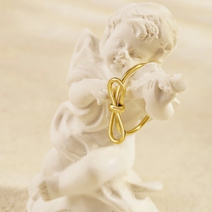 Minimalistischer verstellbarer Goldring mit Knotendesign auf Engelsstatue