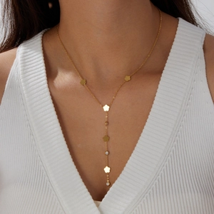 Elegant gold flower Y-shaped long necklace with crystal accents worn on a white knit sweater