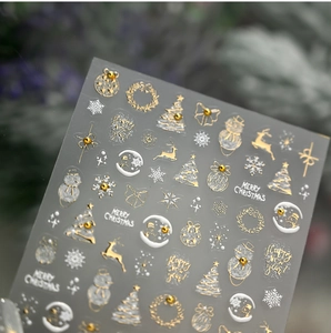 Makro-Detail von Weihnachts-Nagelstickern mit goldenen Rentieren, Bäumen und Schneemännern