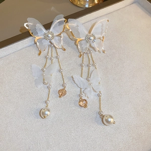 Detailed macro view of butterfly fringe earrings with pearls and crystal accents