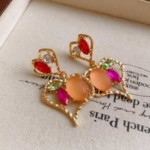 Detail of vintage heart earrings featuring colorful gemstones and gold hammered metal