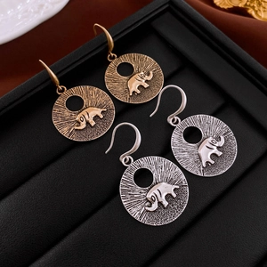Détail de boucles d'oreilles éléphant vintage avec texture radiale et fini doré