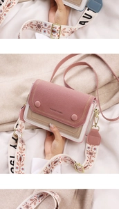 Detail of pink suede crossbody bag with ethnic embroidered wide strap and metal buckle