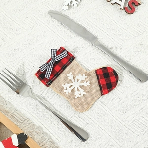 Detail of burlap Christmas stocking cutlery holder with snowflake and plaid bow on table