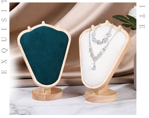 Detail of shield-shaped velvet necklace displays with wooden base on marble