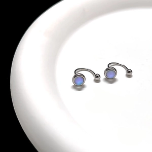 Macro detail of silver moonstone tassel earrings on white ceramic plate with soft light