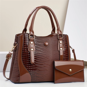 Detail of dark brown crocodile pattern patent leather tote bag with gold metal rivets