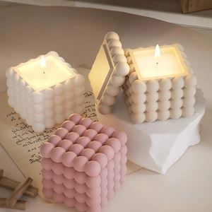 Détail de bougies parfumées cubes à bulles en rose et blanc sur un support papier rétro