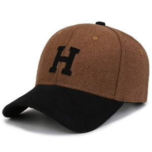 Detail of wool-like baseball cap with brown crown, black brim and embroidered H letter